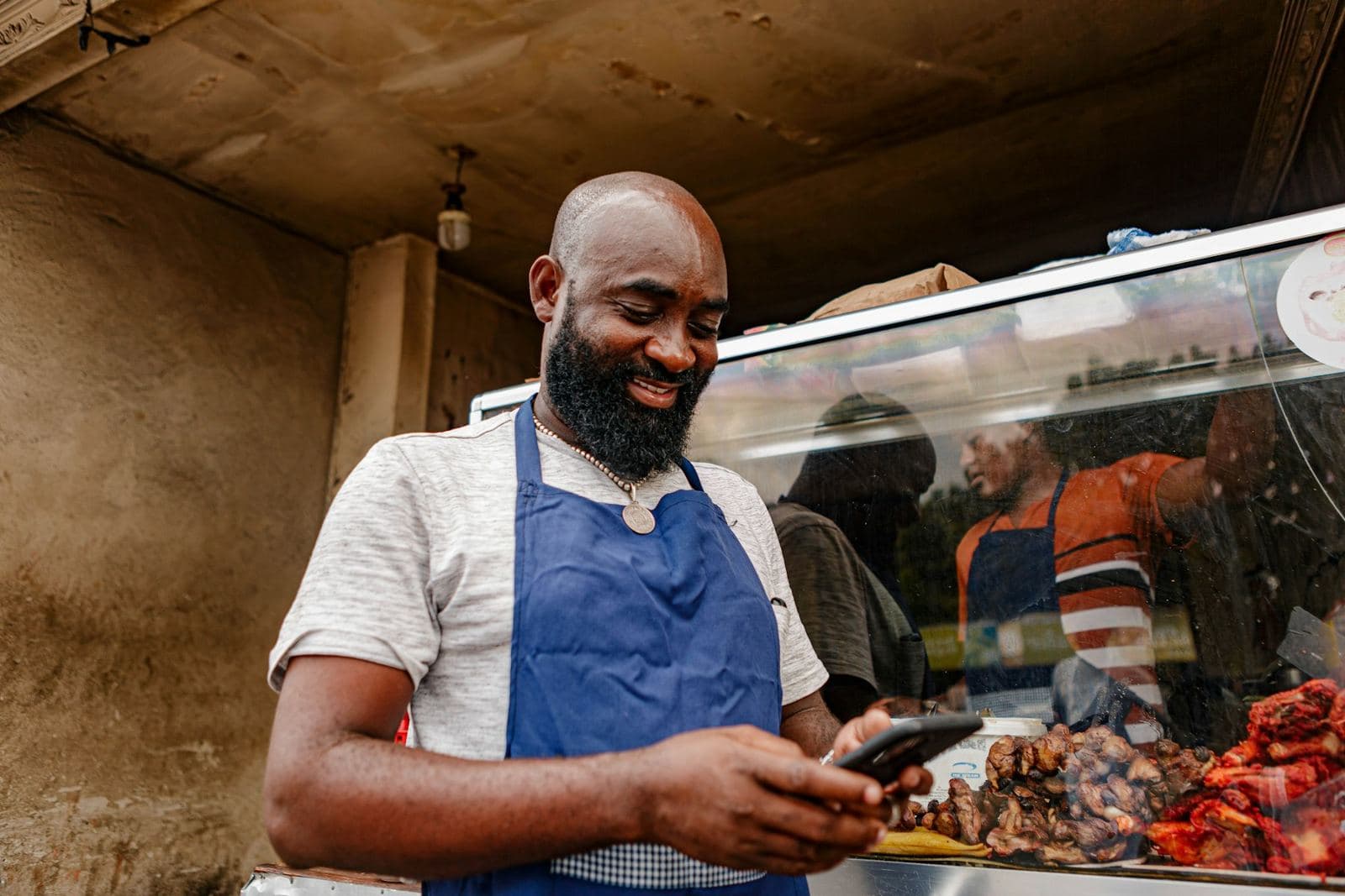A food stall owner answering a message on his phone