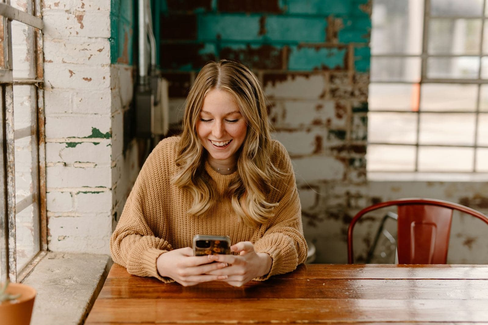 A woman reading a message on her phone at a table